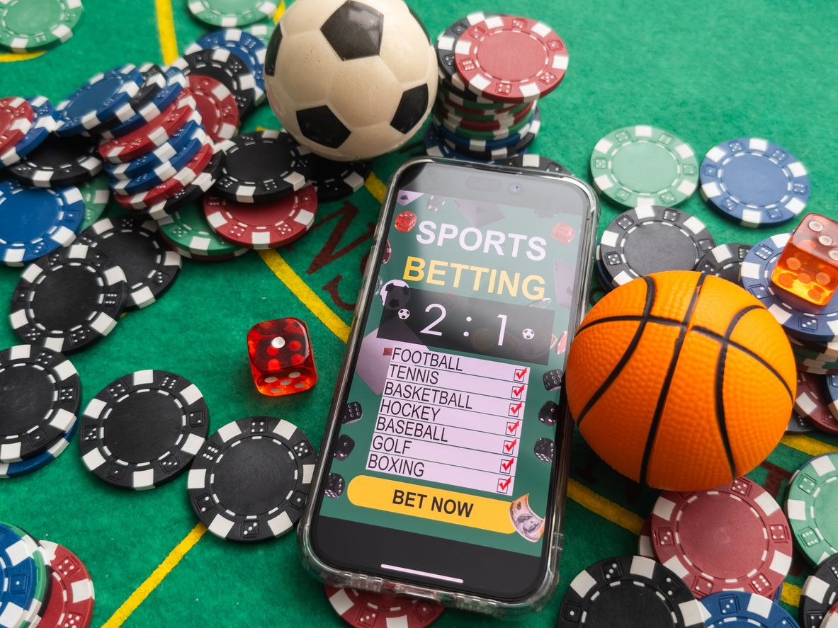 Sports betting screen surrounded by chips and dice on a felt table